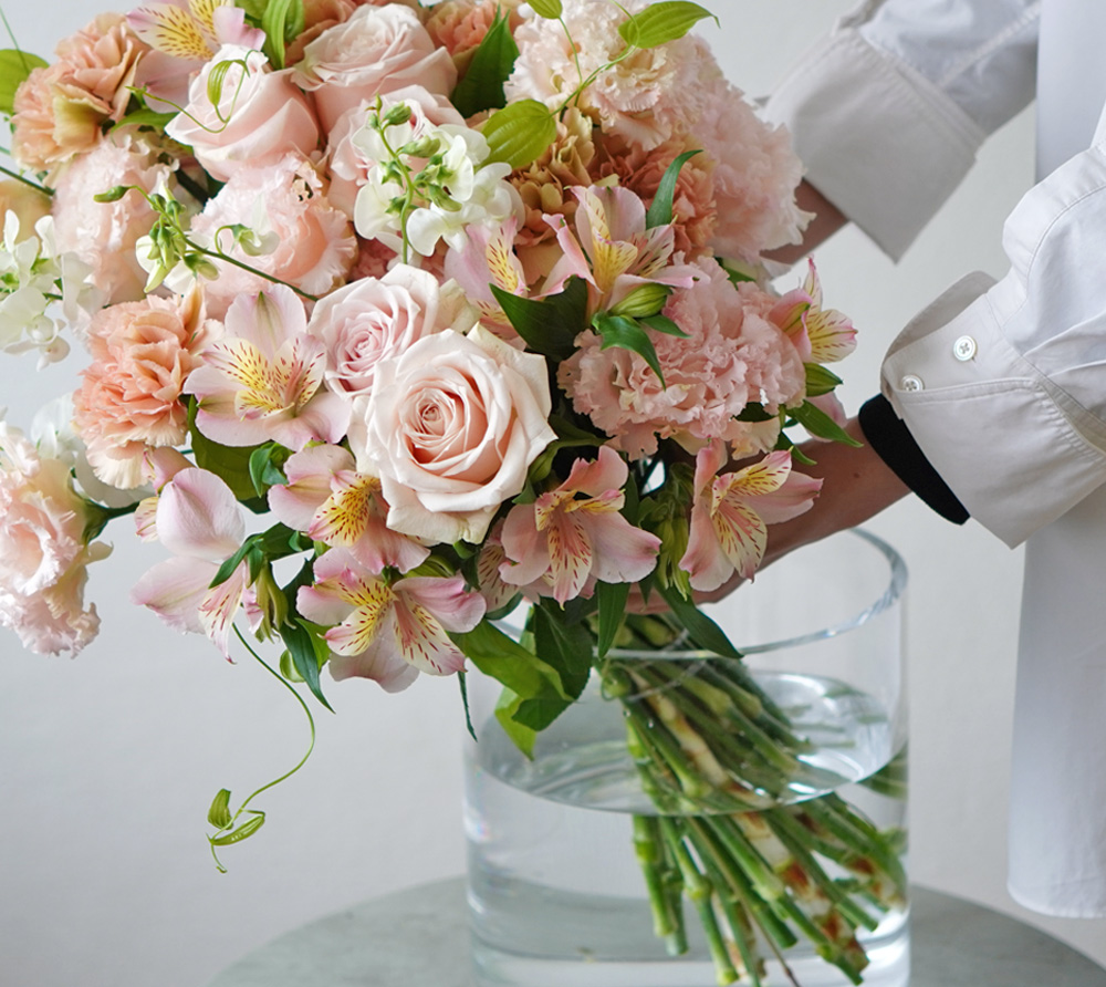 淡いピンクのバラやアプリコットのカーネーションの花束