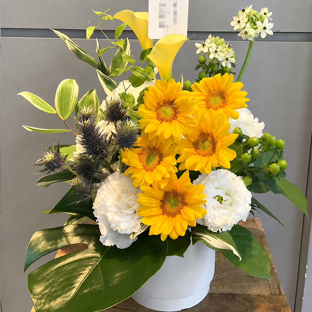 黄色いひまわりと白の花々が鮮やかに映える爽やかなフラワーアレンジメント