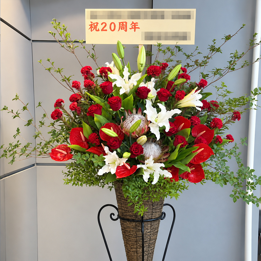 赤と白の華やかな花々でまとめた20周年祝いのスタンド花