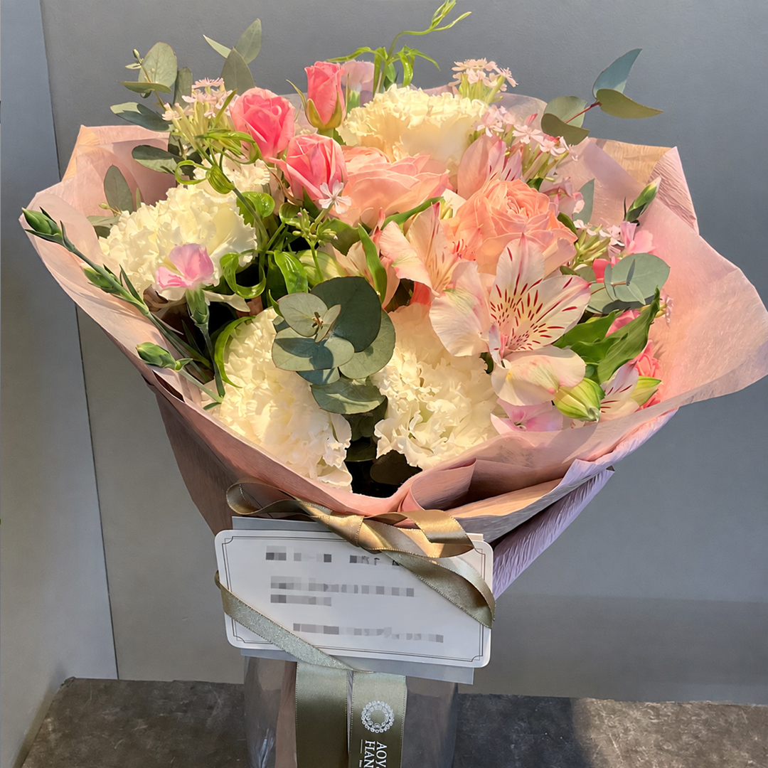 ピンクと白の花々を優美なピンクのラッピングで包んだ華やかな花束