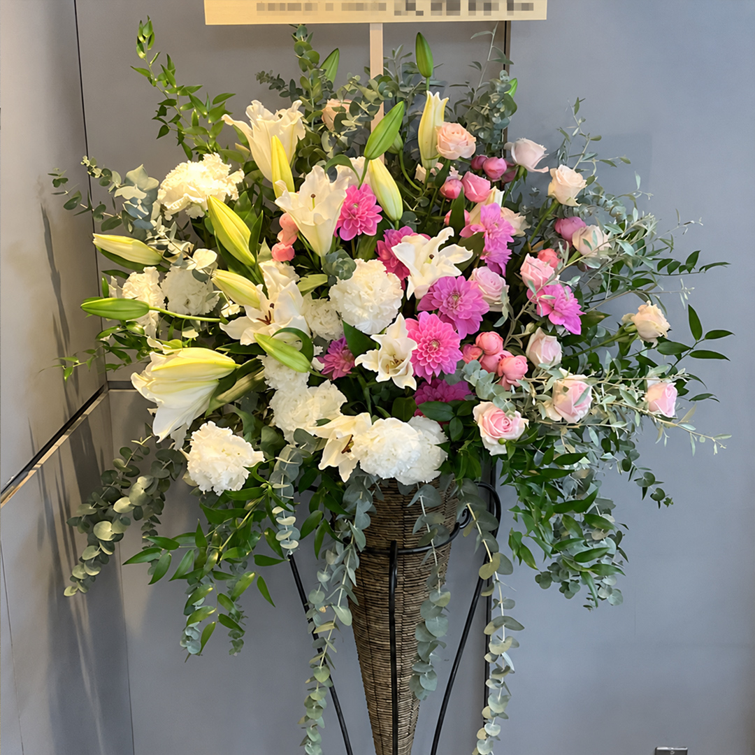 白やピンクの花々と豊富なグリーンで彩られたボリュームのあるスタンド花